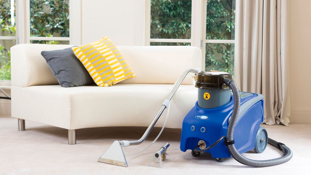 Britex carpet cleaner propped up next to a couch in a living room