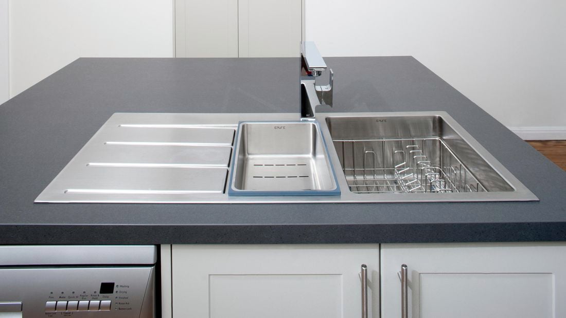 A stainless steel kitchen sink built into a kitchen island complete with dishwasher