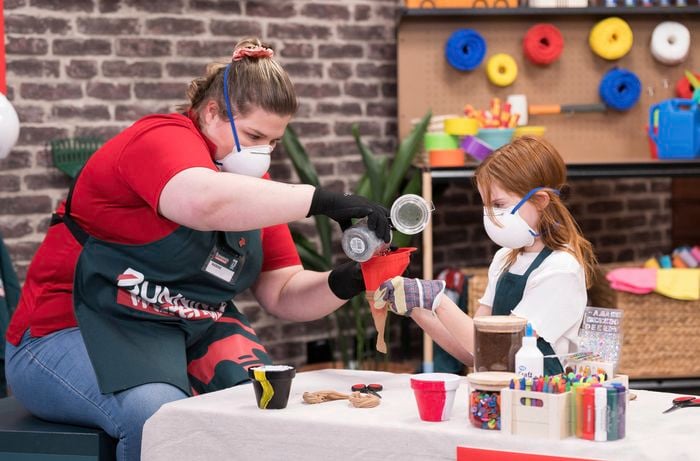 A Bunnings team member is adding peat moss to stockings held by a young girl.