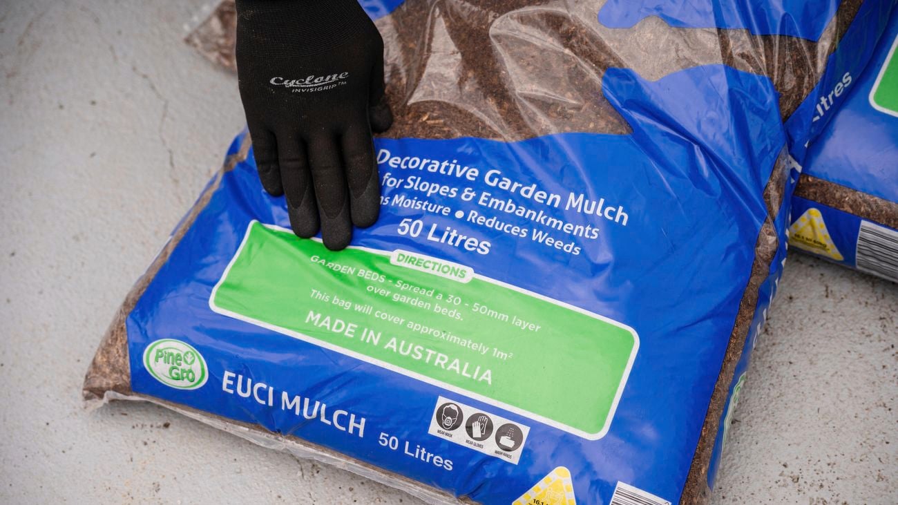 A person touching a bag of mulch