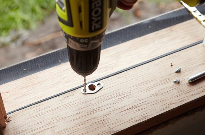 A hole being drilled for a striker plate on a window sill