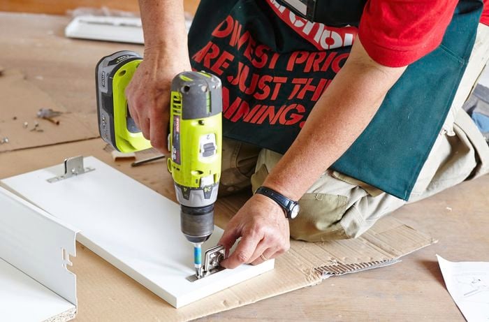 A person attaching a drawer front using a cordless drill