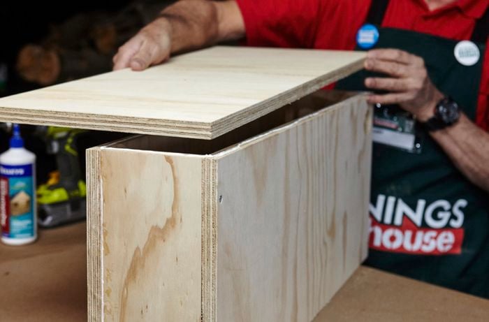 A person attaching a side panel to a plywood box