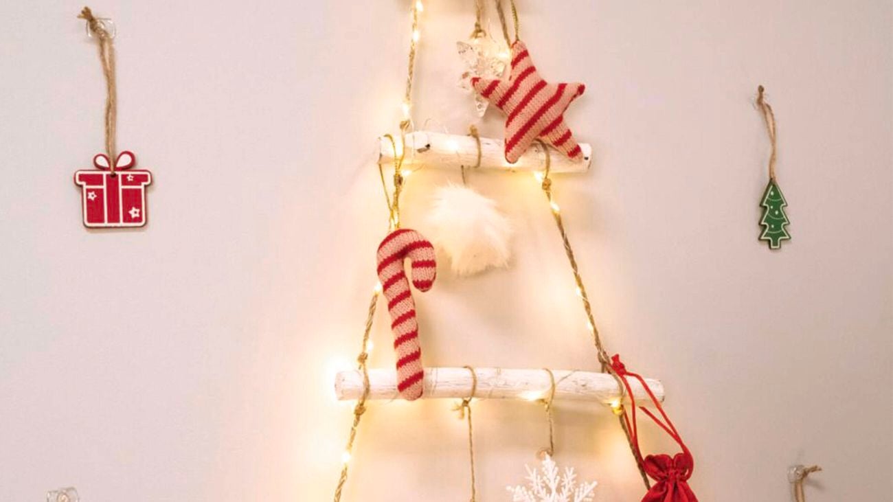 A rustic Christmas tree made with timber rungs, rope and string lights with red and white striped decorations is hung on the all using clear Command hook