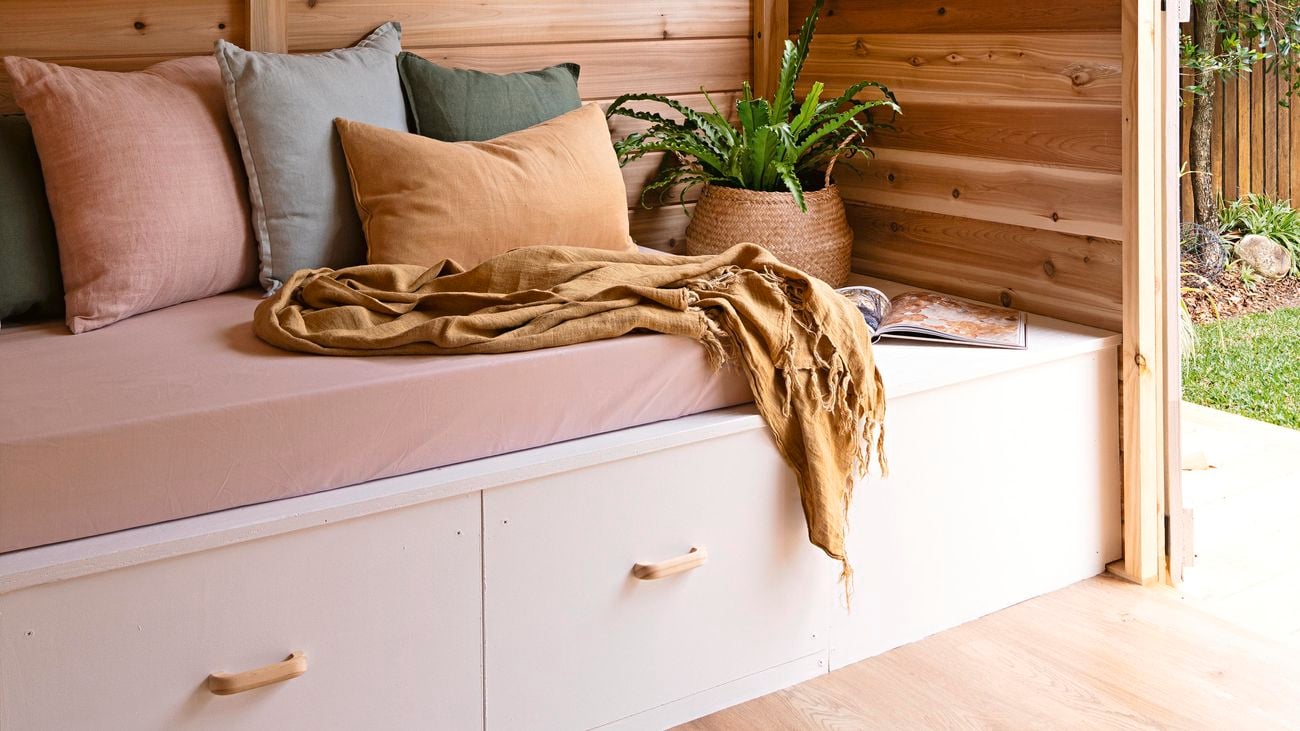 A built-in seat with drawers underneath in a timber lined yoga studio