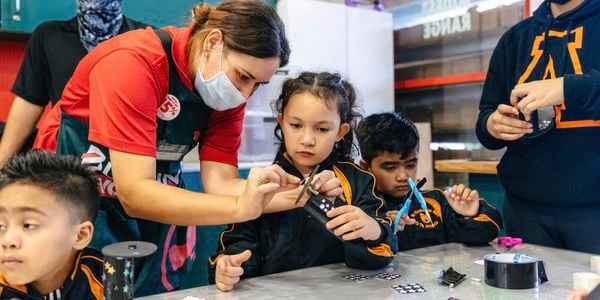 School children assembling Matariki kaleidoscopes with the help of a Bunnings team member