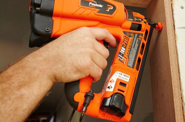 A door jamb being nailed in place with a nail gun