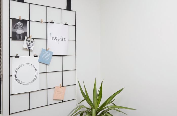 A wire mesh hanger on a wall containing a number of images and messages