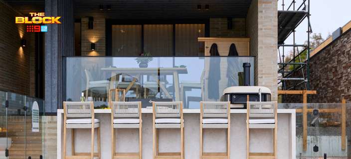 Outdoor entertaining area featuring a poolside bar with timber stools, glass balustrade and covered dining area.