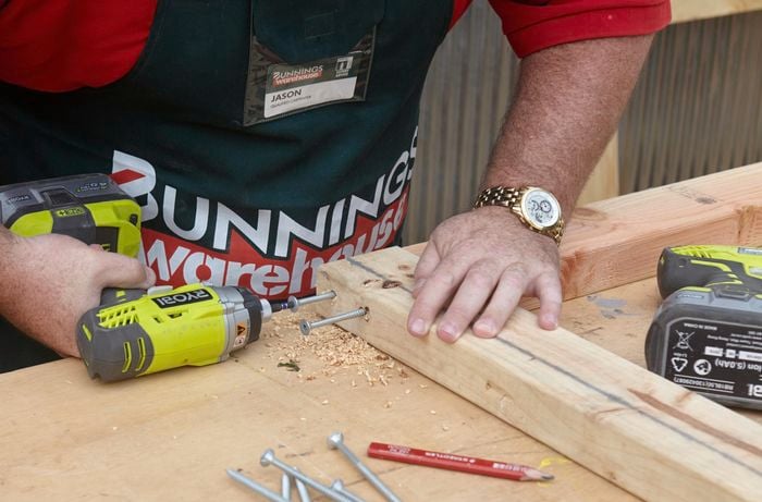 A person joining two pieces of pine at right angles using bugle screws