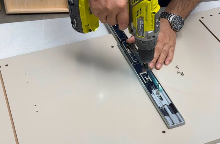 Painted cart sides being predrilled for drawer runners.