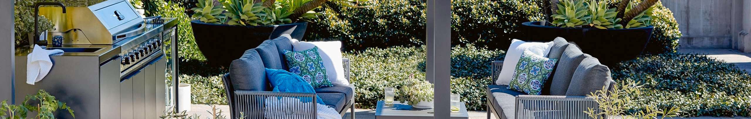 Covered outdoor kitchen and outdoor furniture in a coastal garden setting