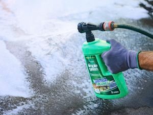 Green Simple Green outdoor cleaner bottle being held by a gloved hand