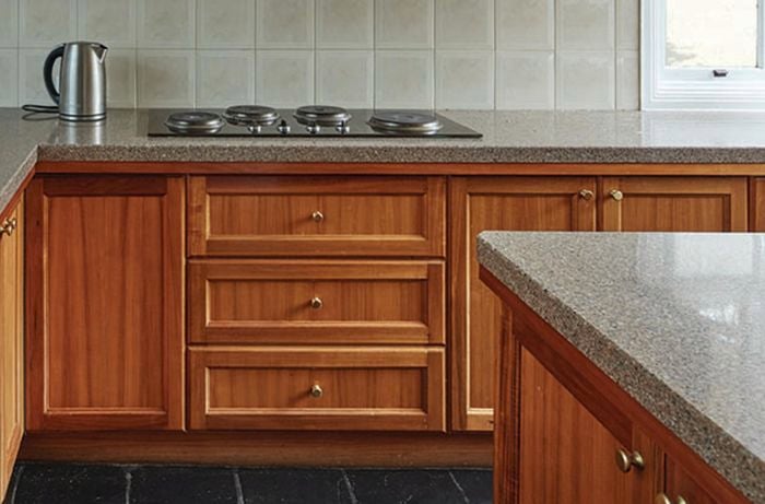 Brown kitchen cabinets with grey benchtop.