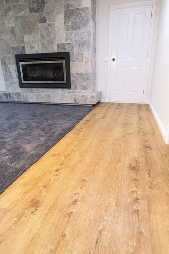 Living room with fireplace and carpet alongside vinyl plank timber-look floor