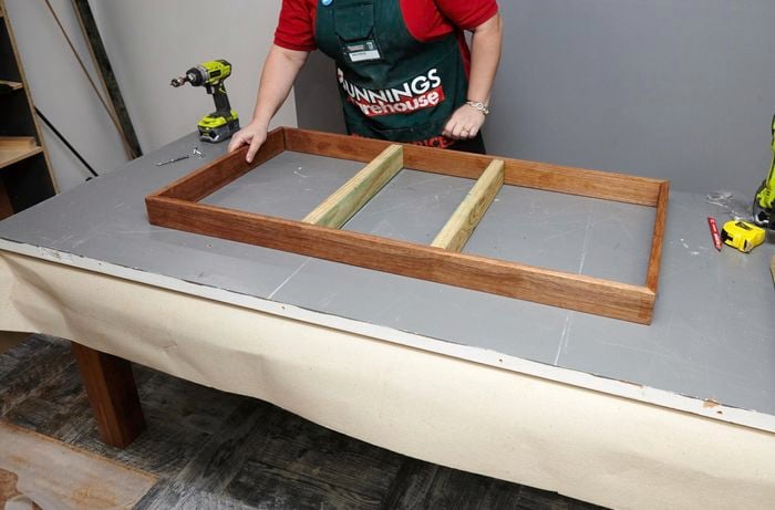 Person laying pine frame on tabletop.