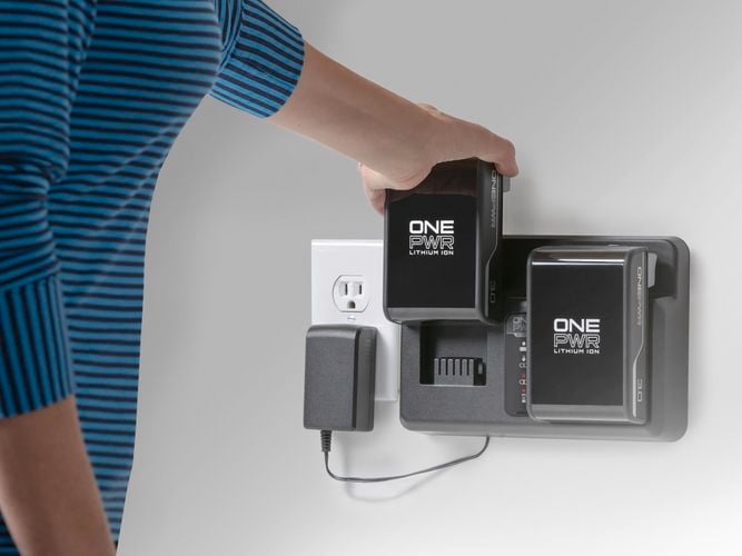 A person plugging in a battery charging station, ensuring convenient power supply for Hoover portable devices.
