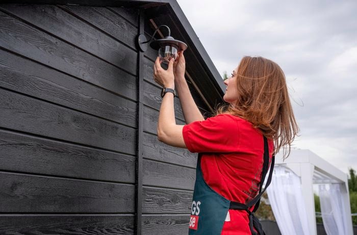 A Bunnings team member affixing a light to the outside of a shed