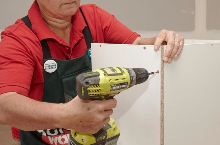 Person drilling panel of cabinet together