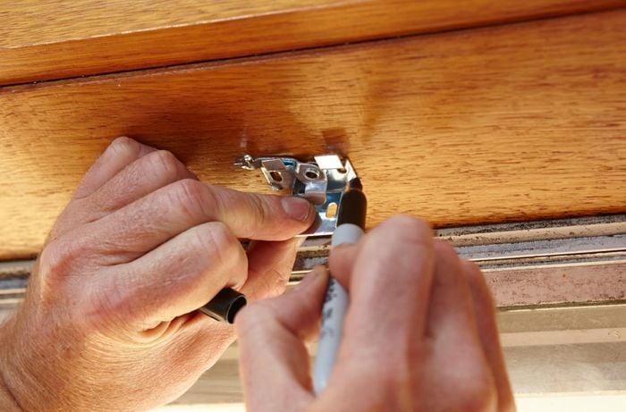 Person using measuring tape and marker to mark up window frame.