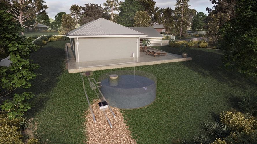 The backyard of a house attached by downpipe to a underground water tank surrounded by shrubs and trees.