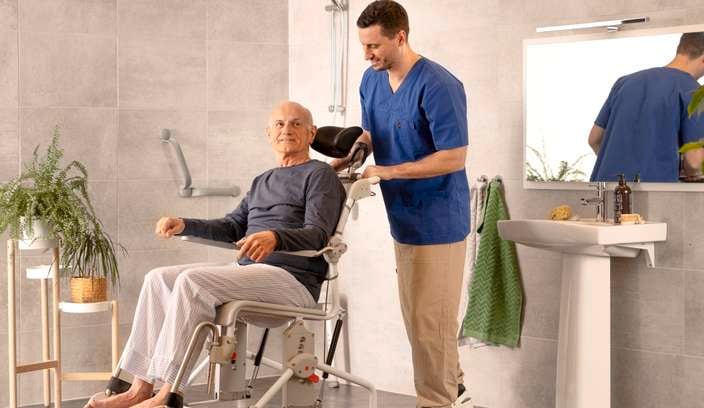 Man in wheelchair, he has a carer with him assisting in the bathroom