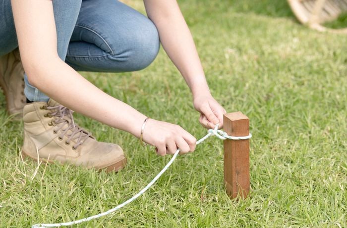 Tying rope around a garden stake.