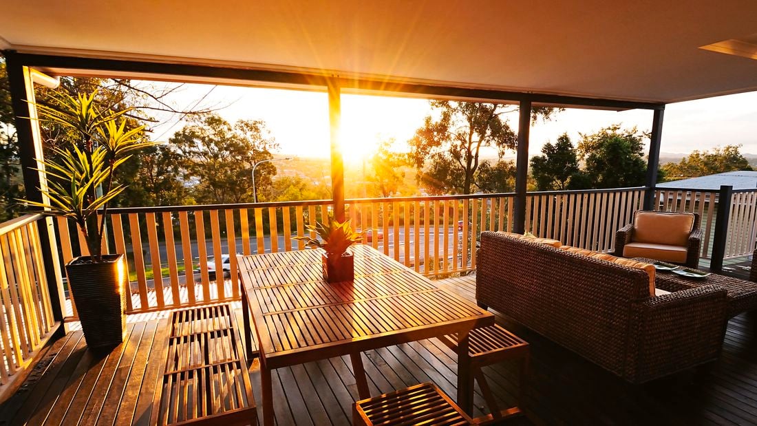 Deck with outdoor table and bench seat, with the sun streaming through.