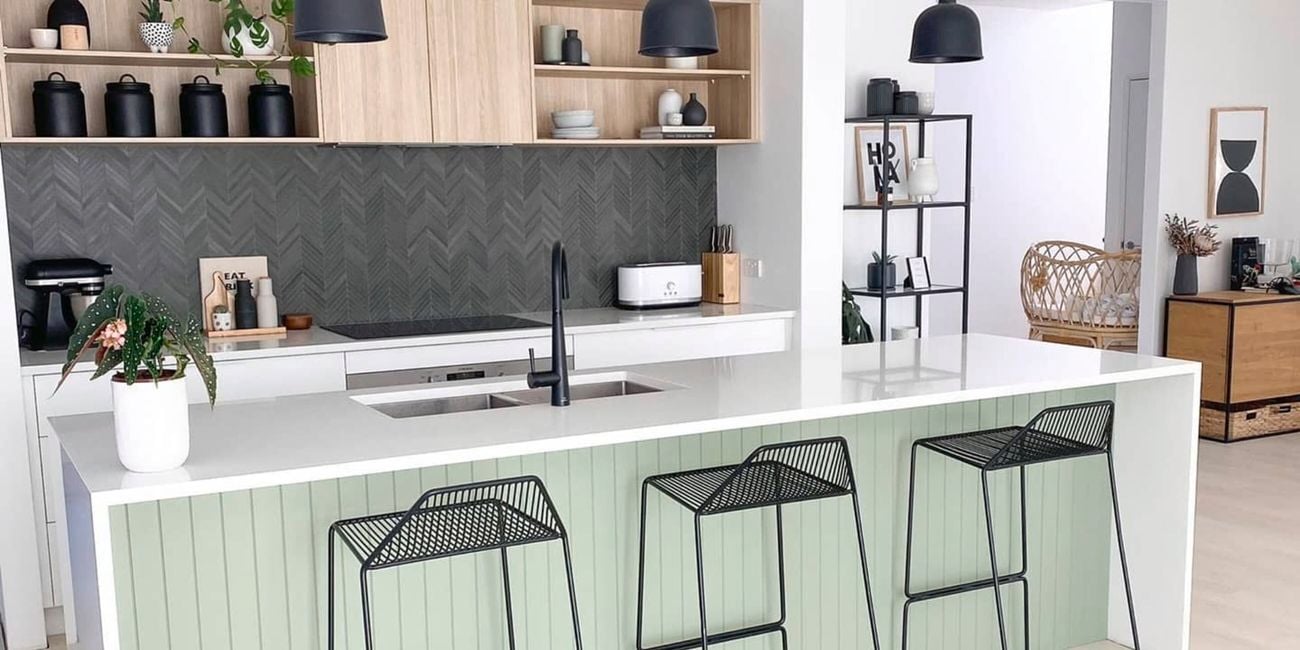 Modern kitchen with an island bench with a white top and green easy vj panelling on the base of it.