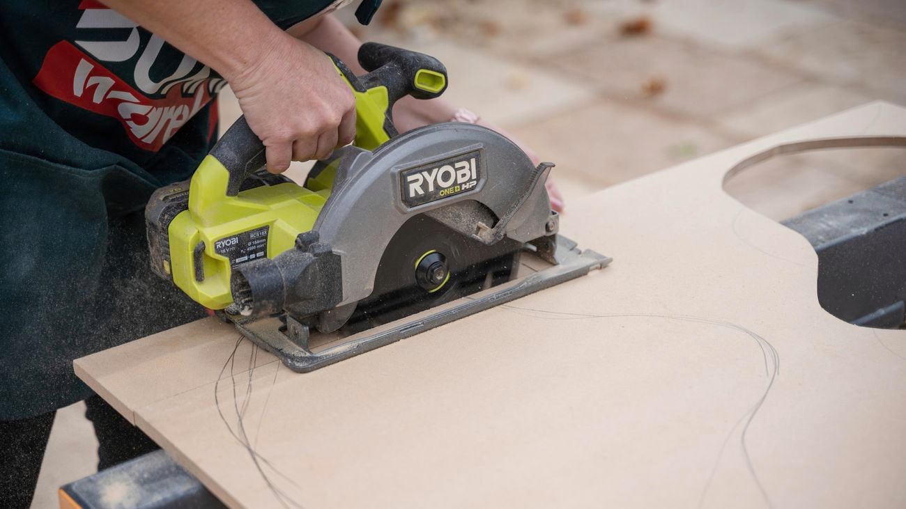 A person cutting a MDF board using a circular saw.