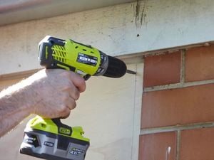 Driving screws through the pilot holes into the frame of the window.