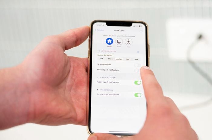 A person is adjusting motion sensitivity and notification preference settings for a front door doorbell on a smartphone app.  