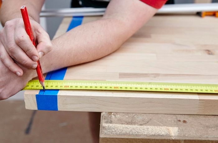 Person measuring piece of timber.