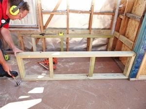 Person wearing ear muffs making a timber frame in a bathroom