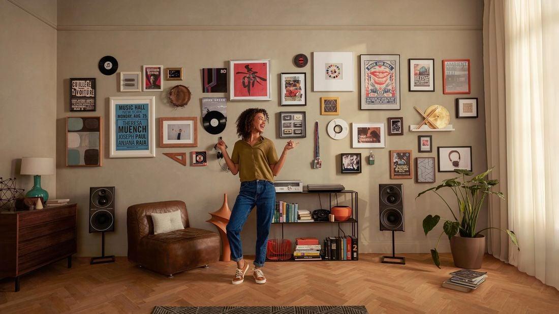 Living room with lady dancing in front of a wall filled with hanging pictures