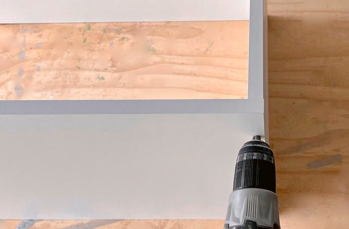 A person pre-drilling into the side of a dismantled cupboard