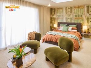 Bedroom with green chairs, patterned feature wall, and earthy-toned bedding.
