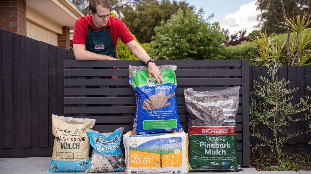 A Bunnings Team Member touching a bag of mulch that is next to other bags of mulch