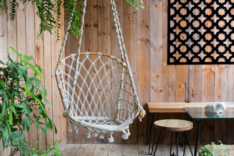 Swinging chair in backyard next to wall with decorative screen