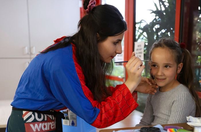 Bunning team member in a costume painting a girls face.