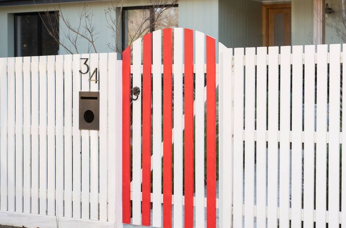 White picket fence featuring a red striped gate design inspired by team colours.