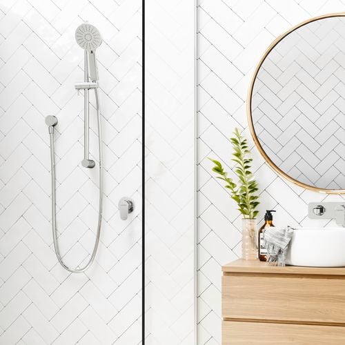 Rail shower head with white tiles from floor to ceiling and scandi furnishings