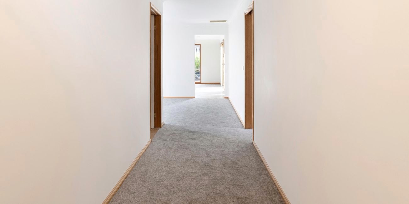 Plain hallway with white walls and grey carpet.