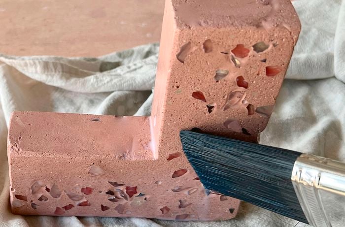 A person brushing sealer on a D.I.Y. terrazzo bookend.