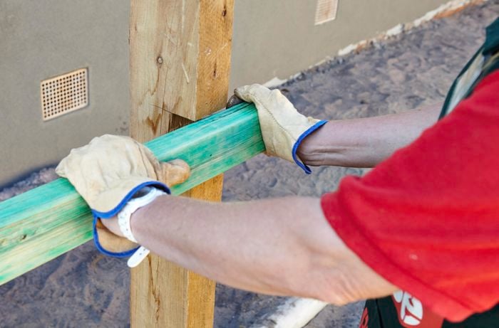 Person inserting timber plinth into cut out spot in timber post.