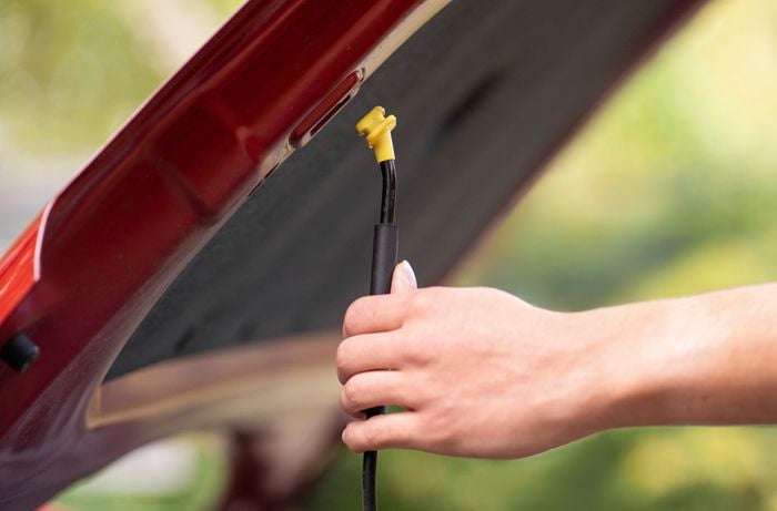 A person is securing the car bonnet with the support rod.