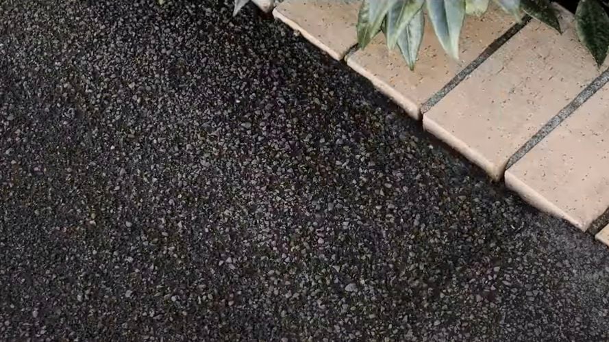 Close up of black/grey gravel path with light-coloured brick border.