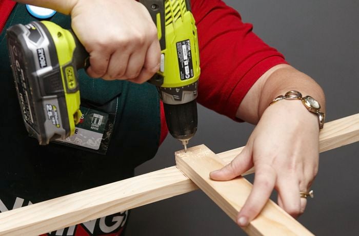 Person drilling bits of timber together to finish book shelf side.