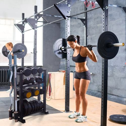 A lady weight training in a gym where dumbbells stored in a rack.