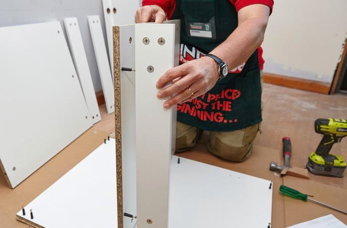 Person attaching rail to shelf panel